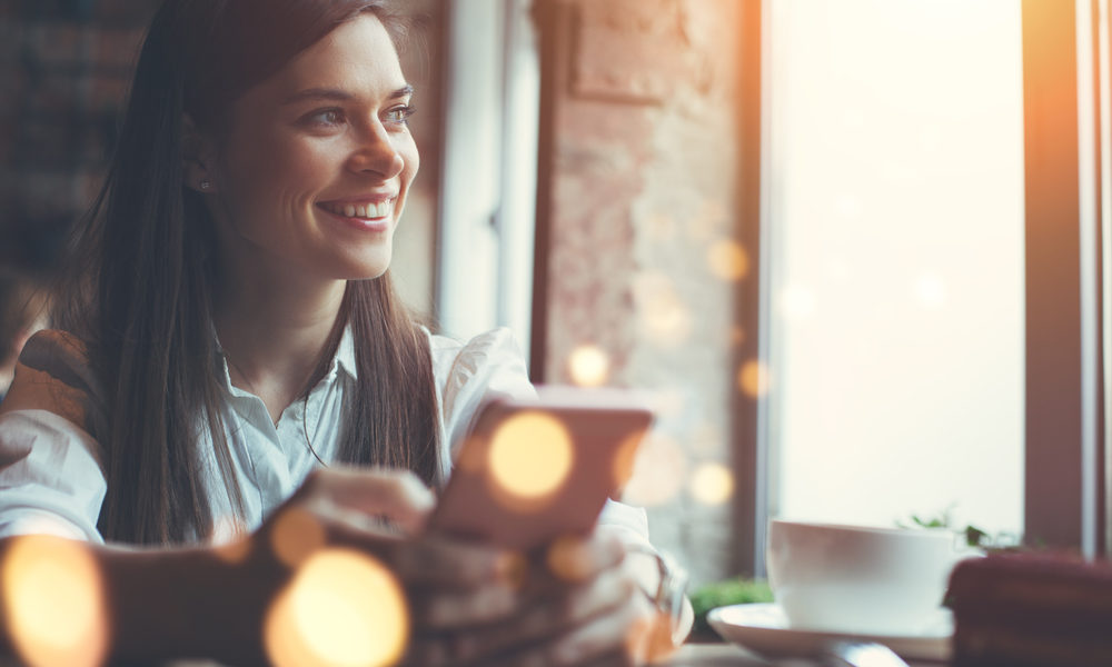 kvinne på kafé med mobiltelefon