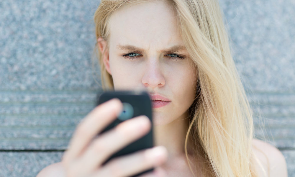 kvinne med mobilapparat misfornøyd