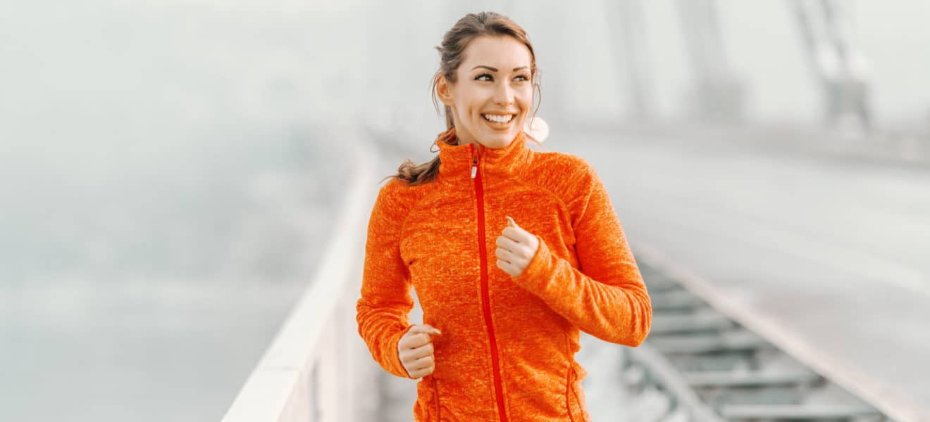 Slik kommer du igang med trening. Dame i orange jakke tar seg en forfriskende løpetur.