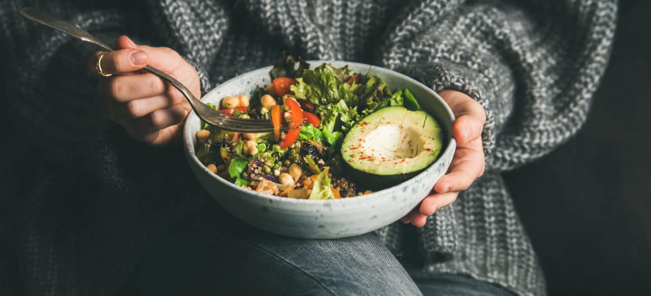 Dame i grå ullgenser spiser en sunn salat, trend-dietter