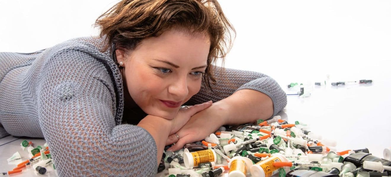 Linda ligger med masse diabetesutstyr som gir diabetesavfall