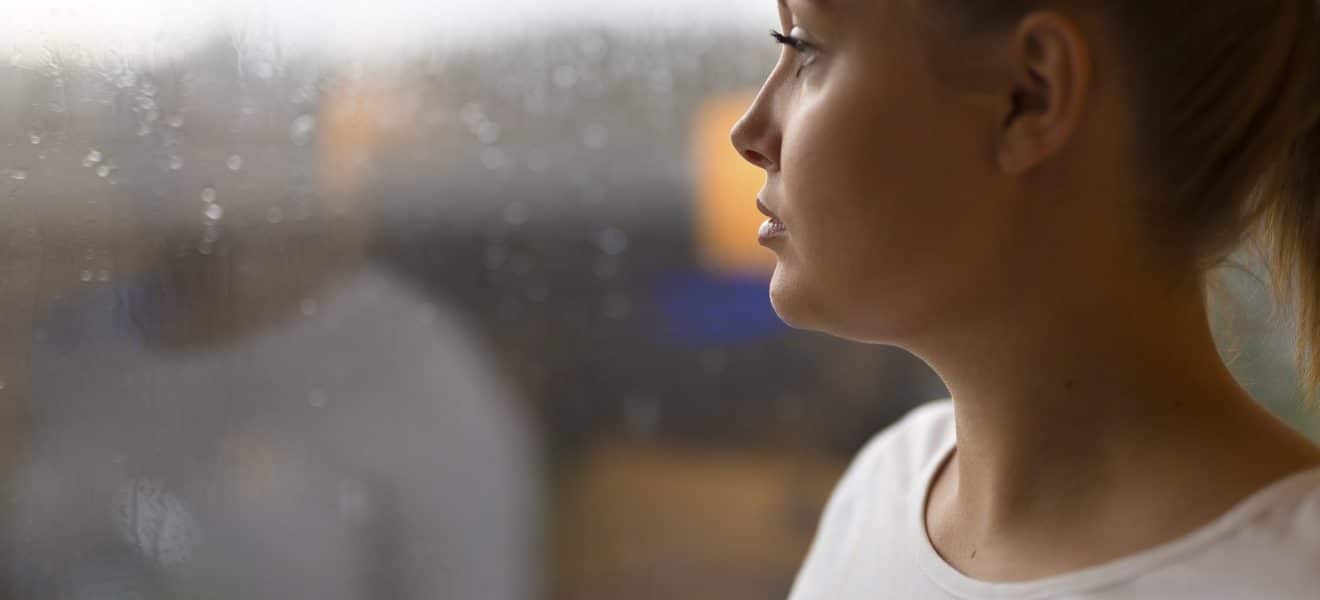 Kvinne med angst og depresjon ser ut av vinduet